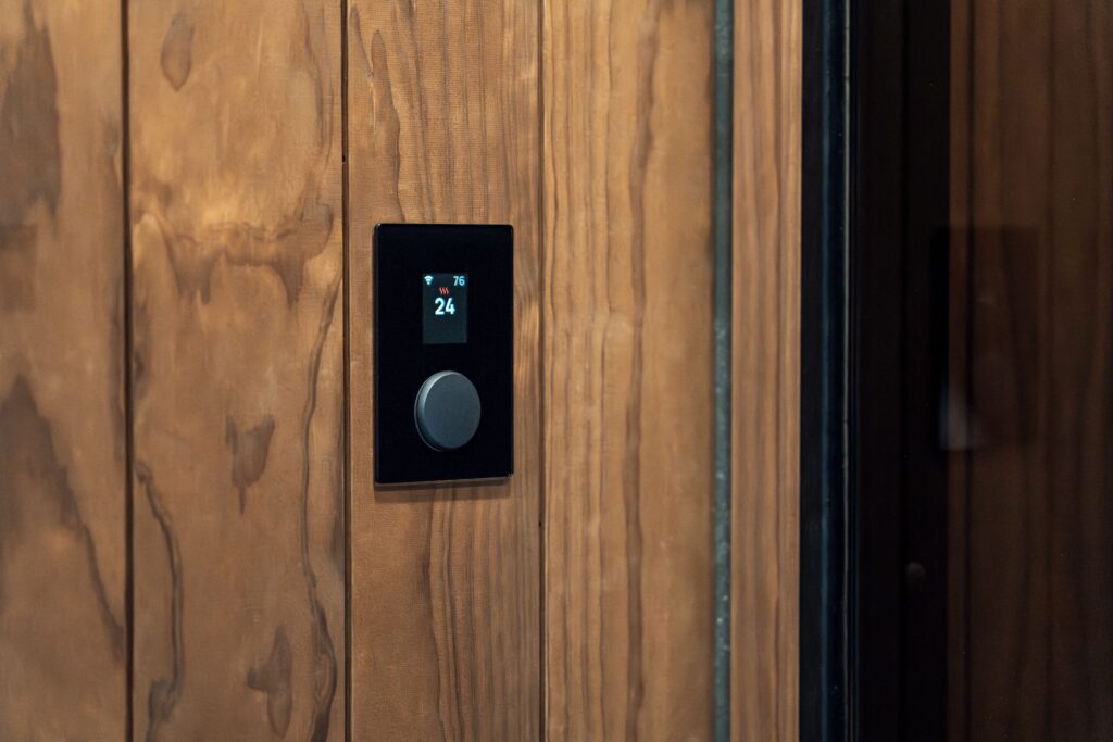 Close-up of a modern sauna control panel featuring a digital thermostat on a wooden wall, highlighting Scandinavian design.
